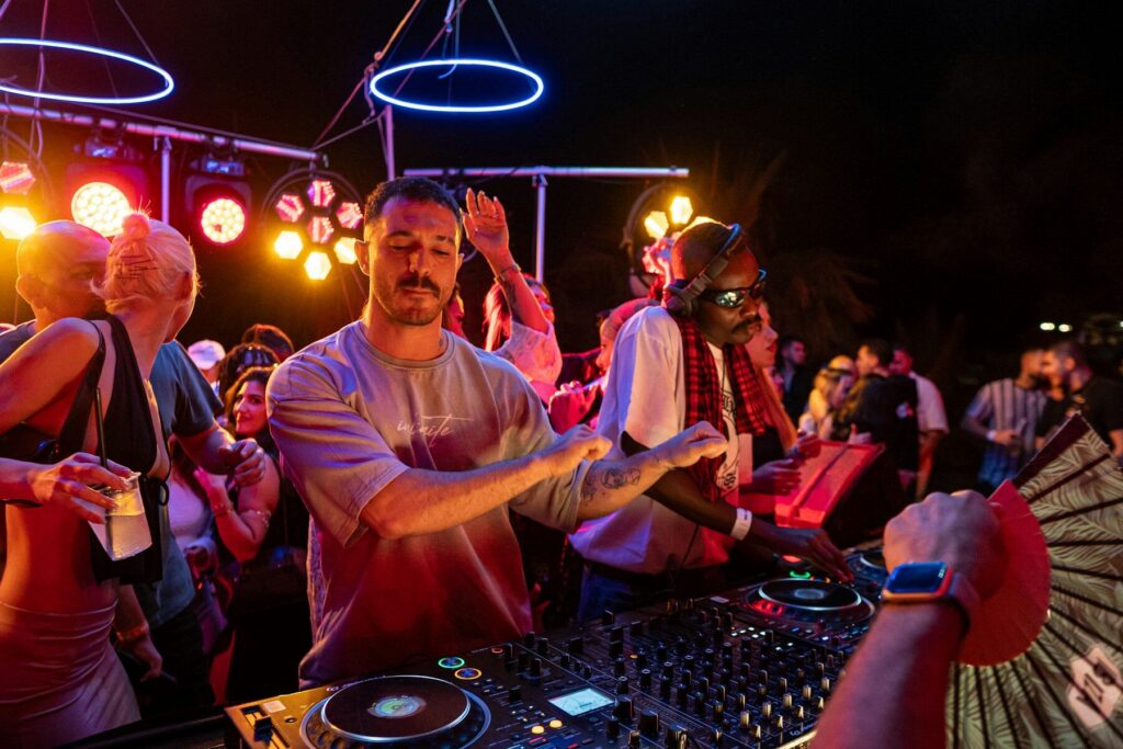 A DJ mixing right in the middle of the crowd with people dancing around him